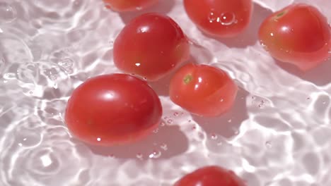 Small-tomatoes-falling-into-a-container-with-water-for-cleaning