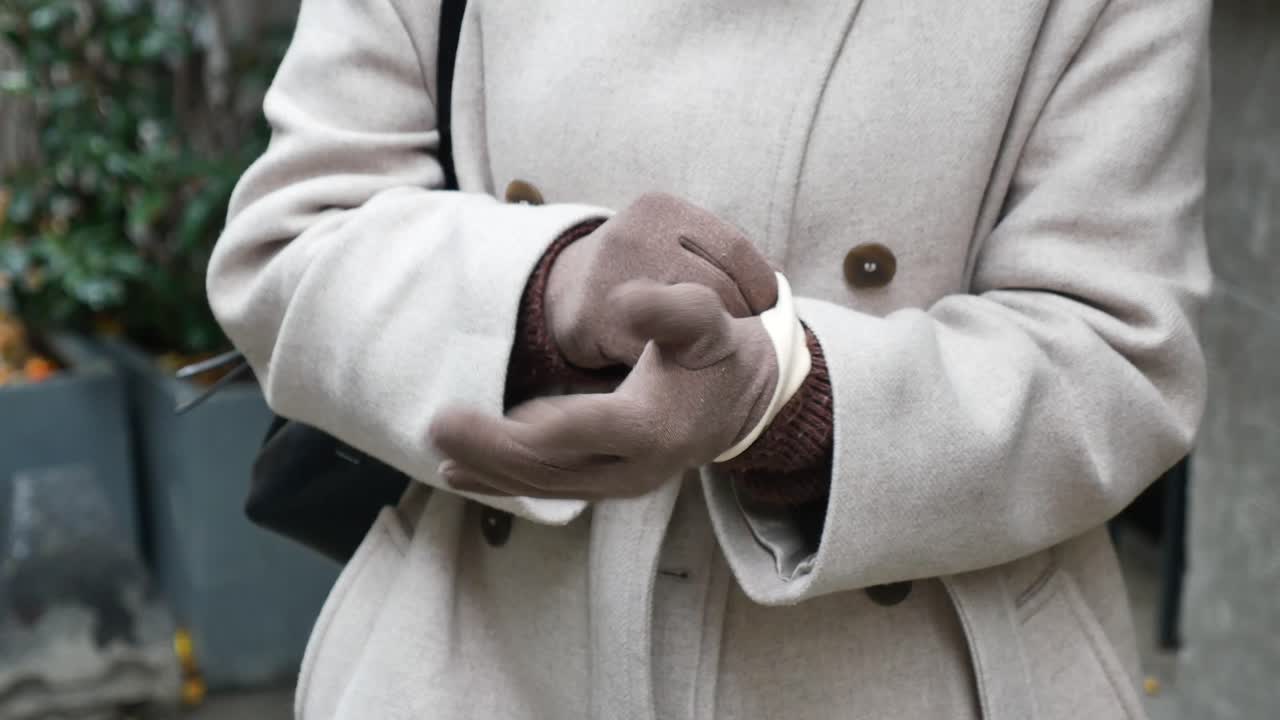 Close-up of Person's Hands Adjusting Brown Gloves While Wearing a Winter Coat