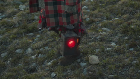 female traveler walking on rocky terrain with old lantern