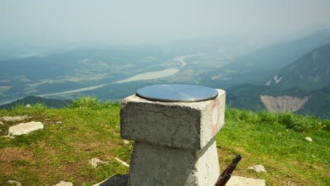 hilltop view from mount golica in slovenia on a clear summer day. the peak offers sweeping views across the border into austria, surrounded by green slopes, distant mountains, and blue sky.