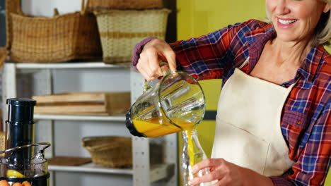 Woman-pouring-orange-juice-into-a-bottle