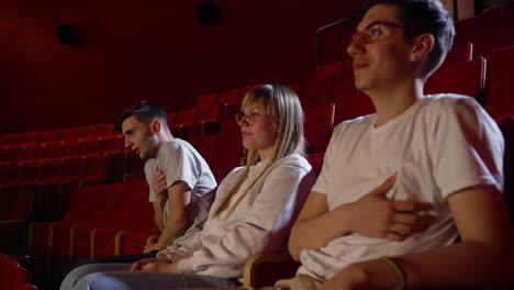 adolescent friends watch a scary movie on the big screen, side view