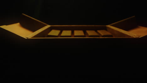 a hand carefully arranging gold bars into a box - close up, pullback shot