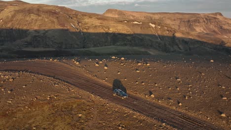 drone view of an off-road vehicle navigating a rocky trail in the remote icelandic highlands, surrounded by rugged mountains and barren terrain