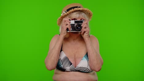 Senior-woman-tourist-photographer-in-swimsuit-taking-photos-on-retro-camera,-smiling-on-chroma-key