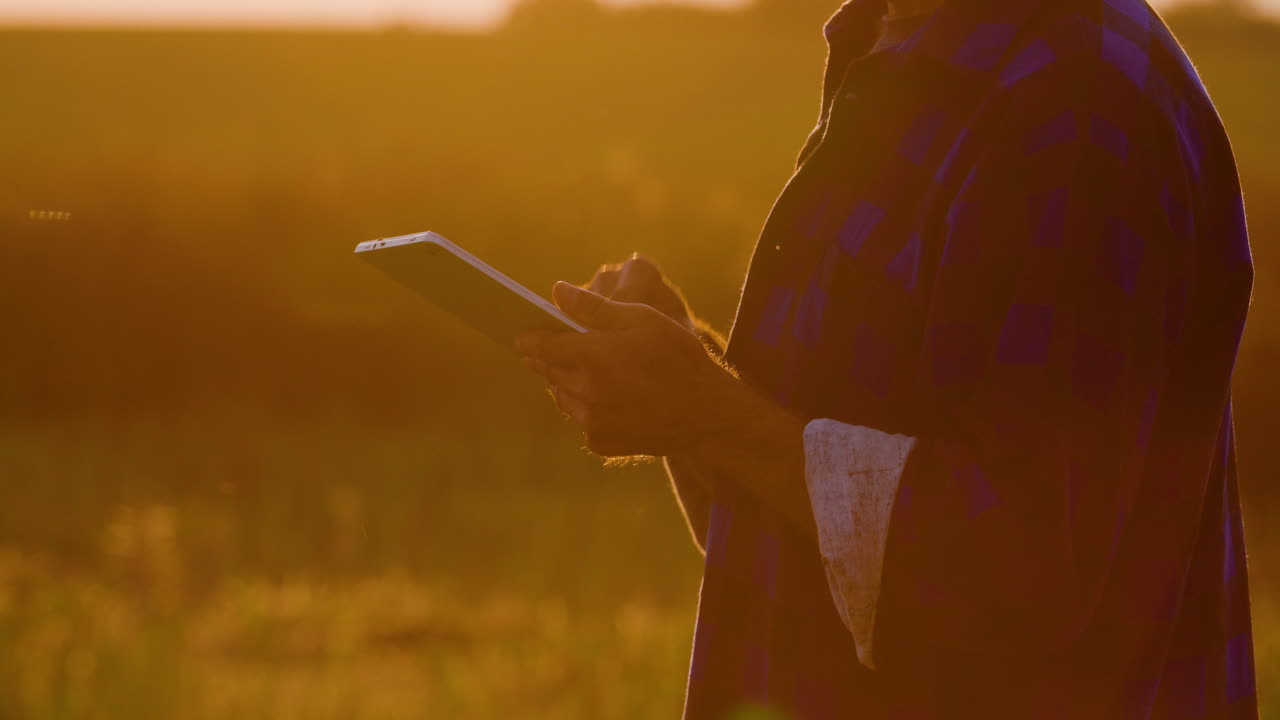 granjero que usa una tableta digital en la granja contra la puesta de sol 1