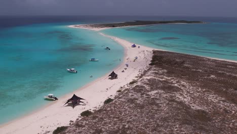 aerial view of cayo de agua featuring serene beach, clear turquoise waters, boats, tranquil mood, overcast sky