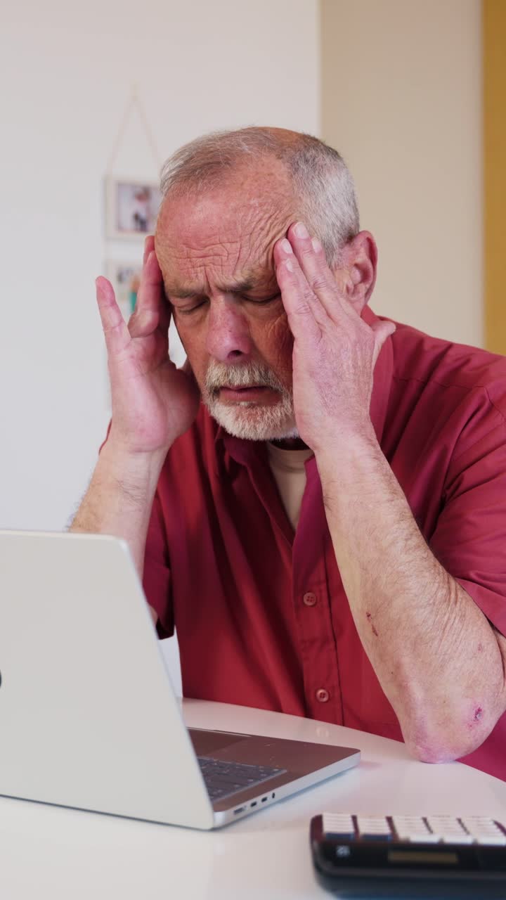Stressed Senior Man Experiencing Headache While Working on Laptop