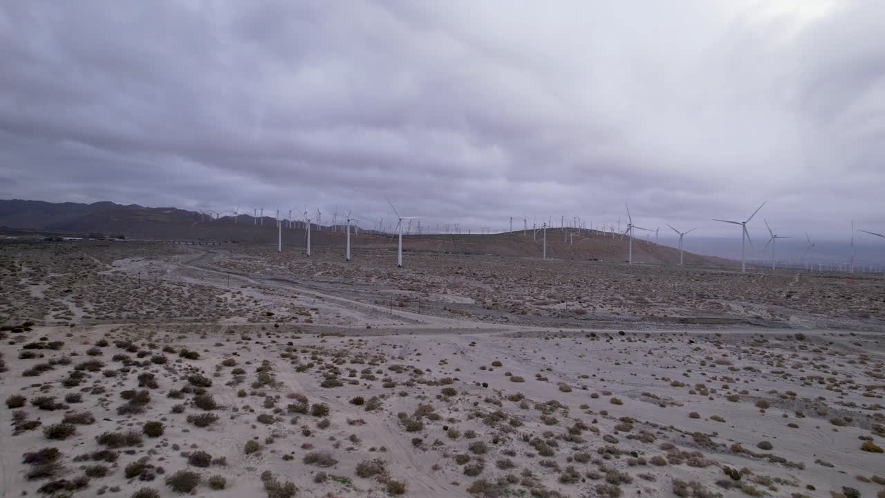 Filmato aereo di un parco eolico nel deserto di Palm Springs in una giornata nuvolosa, con ampio zoom da carrello e gru.