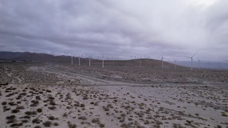 Aerial-footage-of-a-wind-farm-in-the-Palm-Springs-desert-on-a-cloudy-day,-wide-dolly-crane-zoom