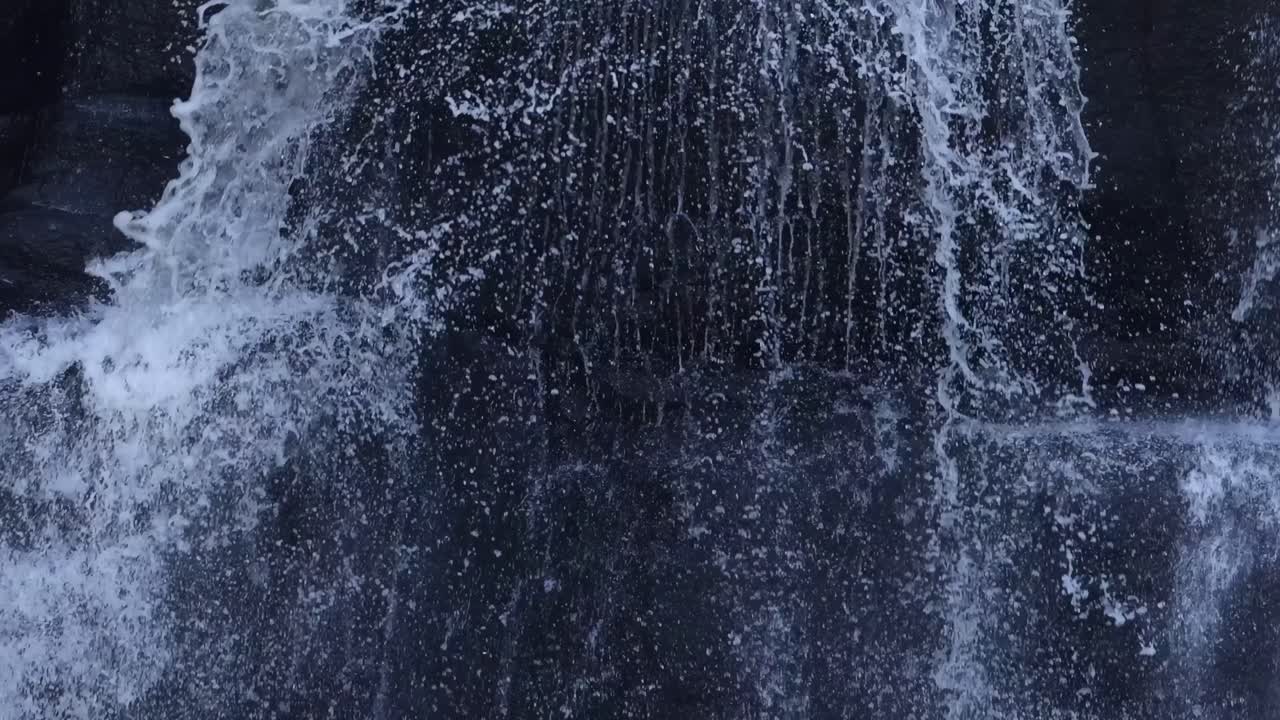 Detailed view of water splashing down a rocky surface, capturing the dynamic flow and texture.