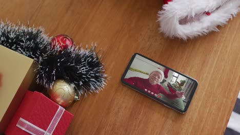 Un-Hombre-Afroamericano-Albino-Sonriente-Con-Sombrero-De-Papá-Noel-En-Una-Videollamada-Navideña-En-Un-Teléfono-Inteligente