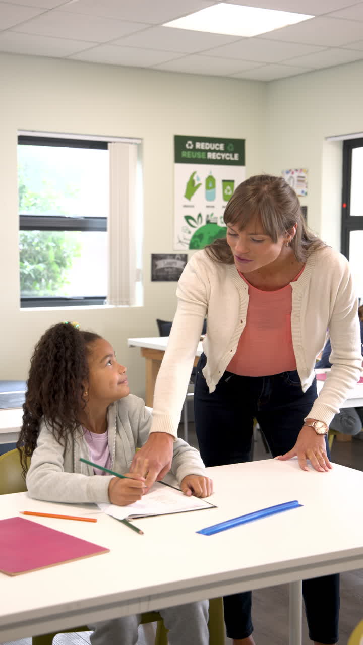 Vertical video: helping student with homework, teacher fostering learning in classroom