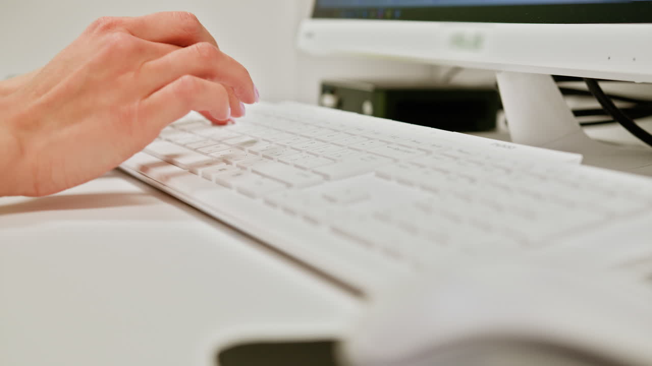 mujer escribiendo en un teclado en un escritorio de computadora
