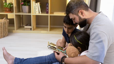 side view of father, son and daughter in the living room.