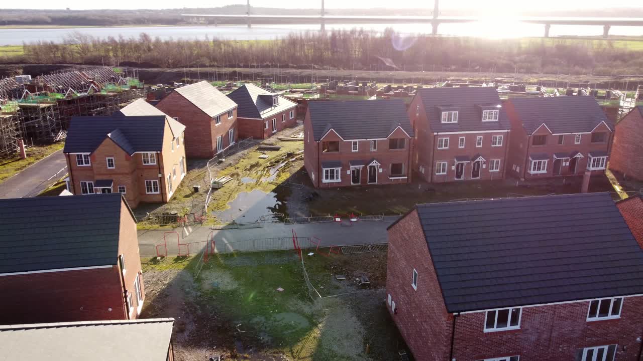 Luftfoto af ufærdig byggeplads for rækkehusprojekt ved vandet, der kredser mod venstre.