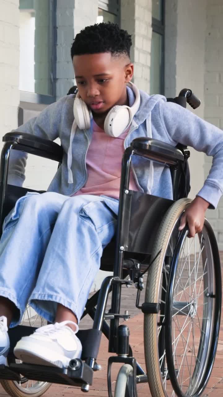 Vertical video: Gripping rims, teen in wheelchair pushing along brick walkway, keeping momentum