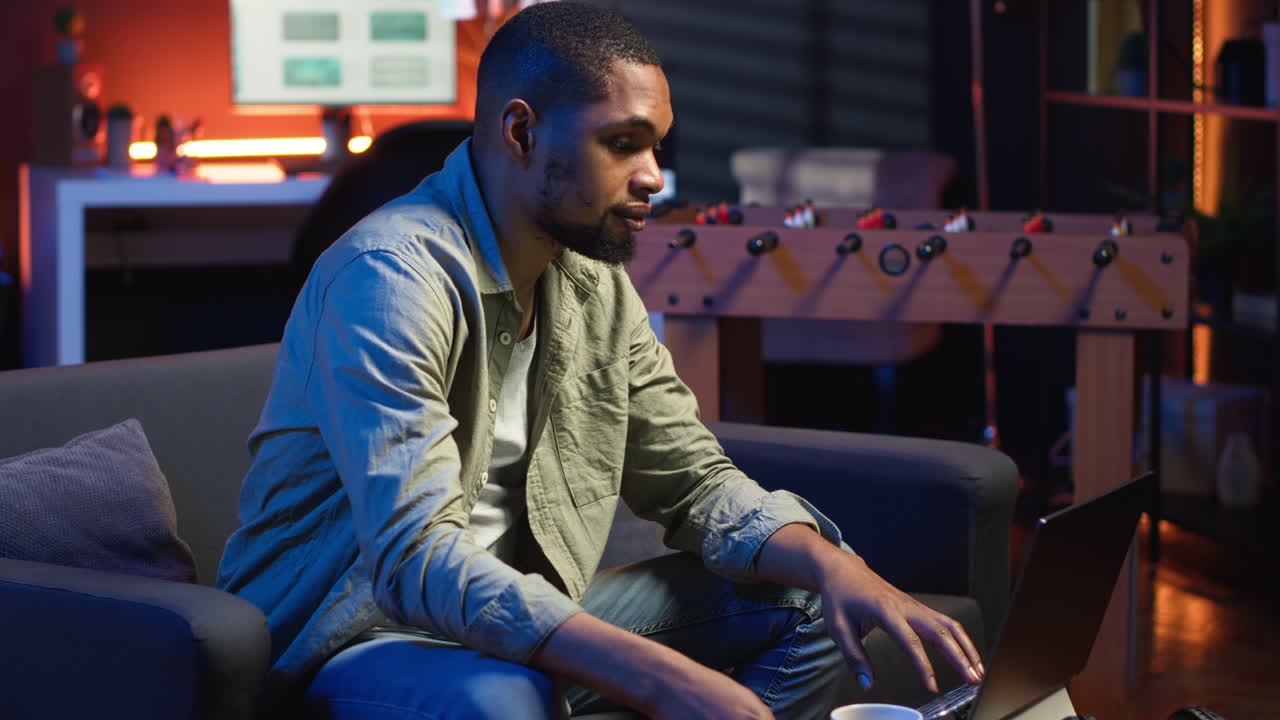 Vertical Video Young black guy working on his freelance tasks in the living room