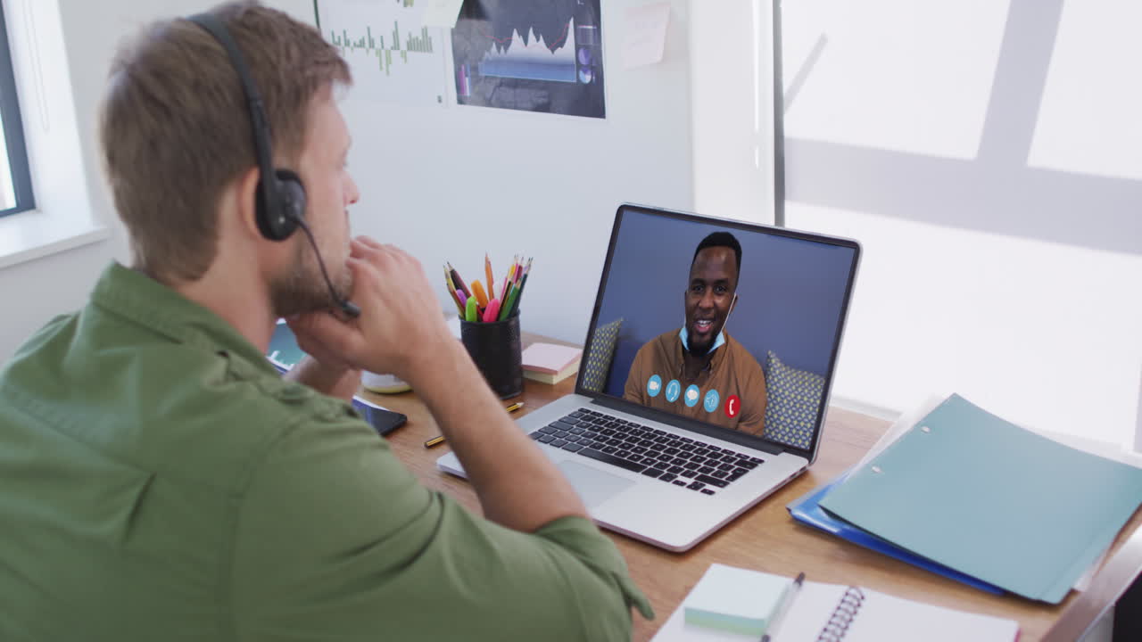Caucasian man on laptop video chat wearing phone headset at home