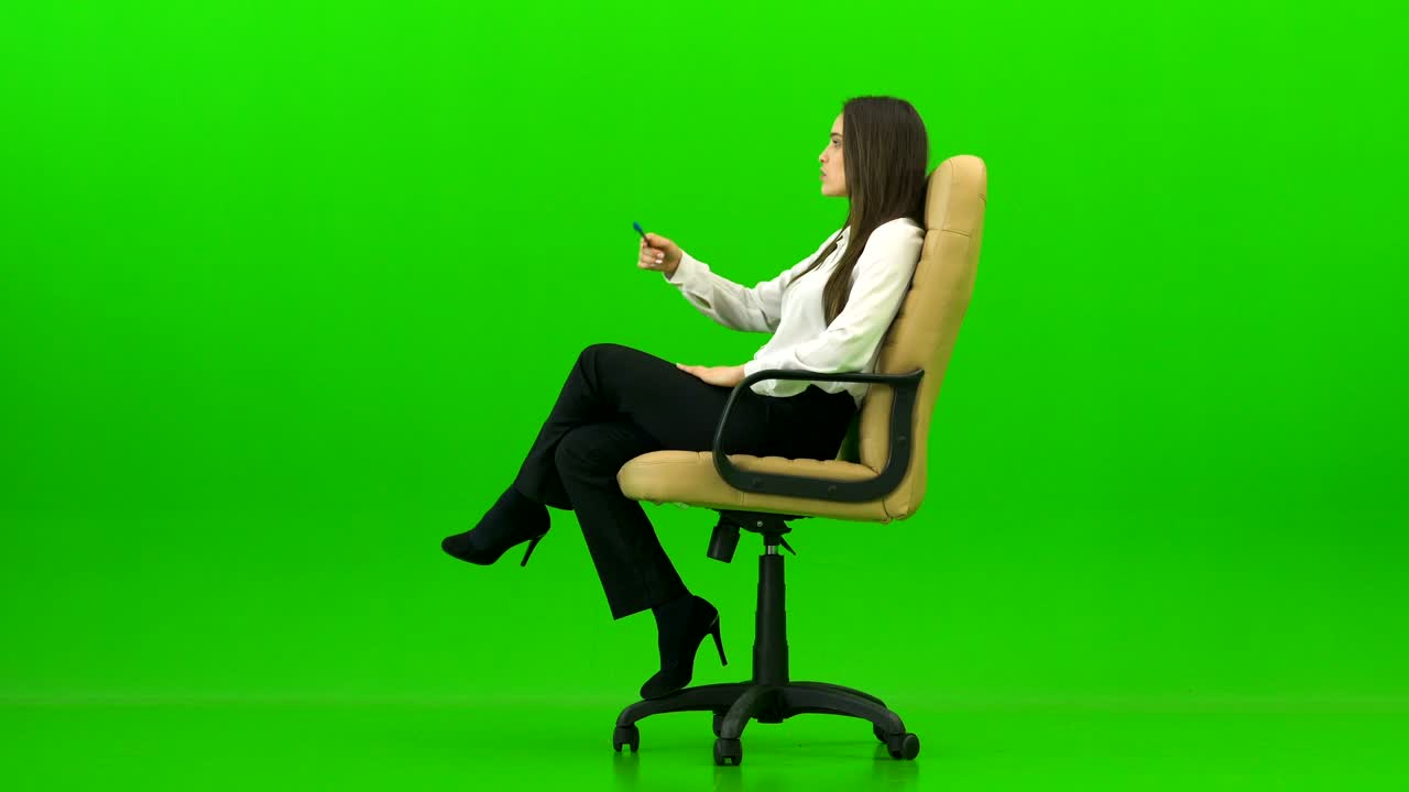 The woman on the office chair talking on the green background