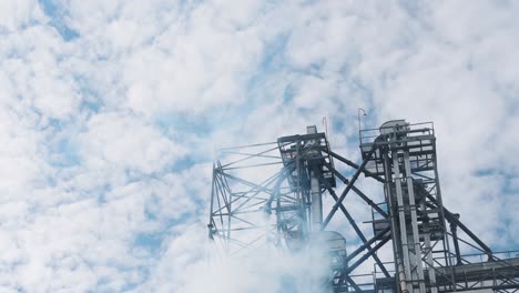ecological problems. high construction of a factory in the sky. white steam near the metal construction of a large manufacturing