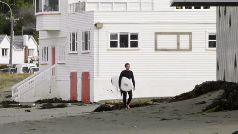 a surfer walking in lyall bay, wellington, new zealand - tracking shot