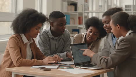 group of young adults collaborating and discussing content on a laptop