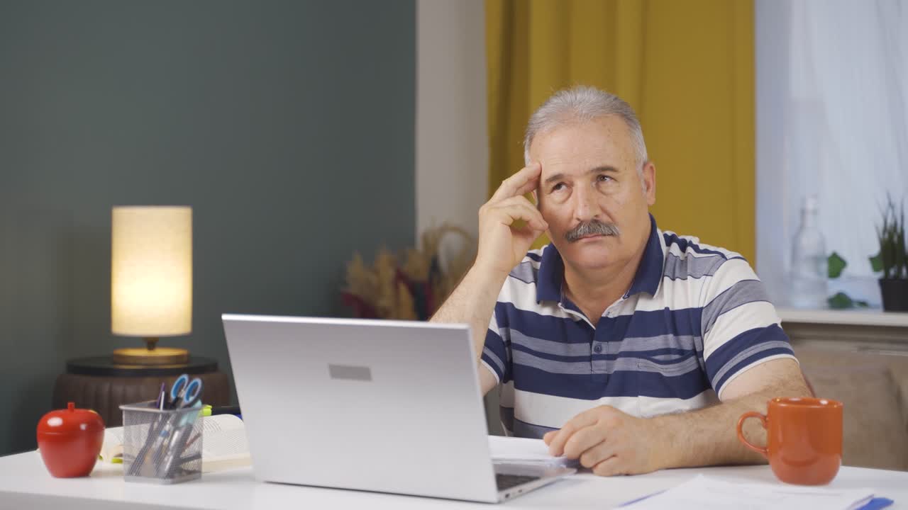 Home office worker old man thinking looking at camera.
