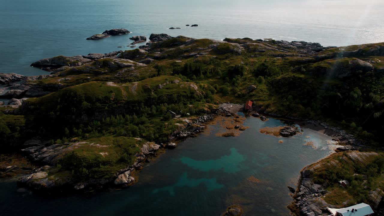 Aerial shot of a quiet Lofoten island with traditional red cabin on Norway’s rugged coastline.