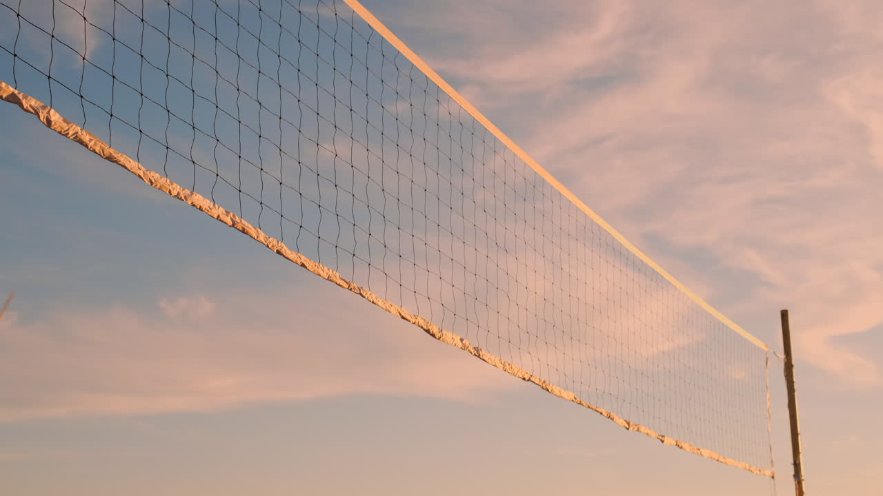 Group of young girls playing beach volleyball during sunset or sunrise slow motion. Beautiful girls in bikini professionally play volleyball on the sand