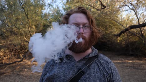 el hombre pelirrojo muestra vape a la cámara y luego fuma.