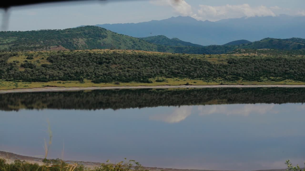 turista en safari toma una foto del pintoresco paisaje africano reflejado en el lago