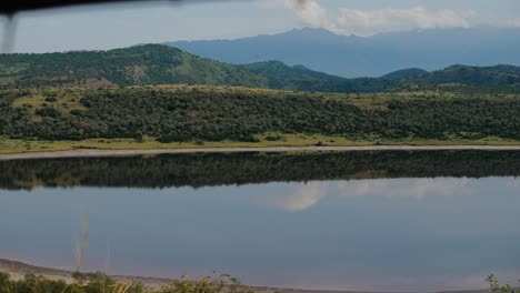 tourist on safari takes picture of scenic african landscape reflected in lake