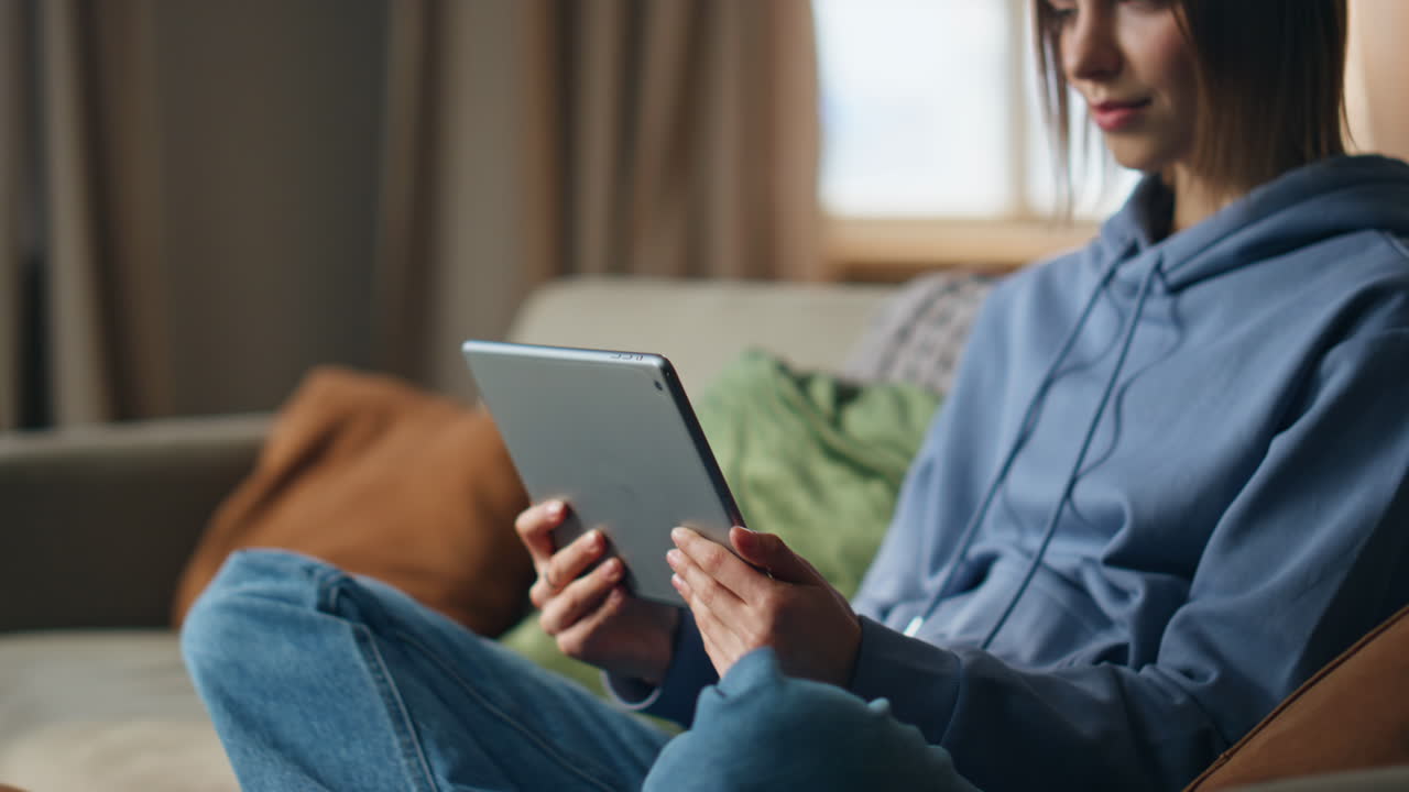 A woman uses a tablet on the couch