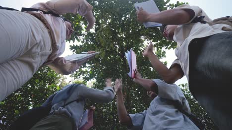 low angle shot of happy teenage people stacking hands together and giving high five to each other showing teamwork and cooperation
