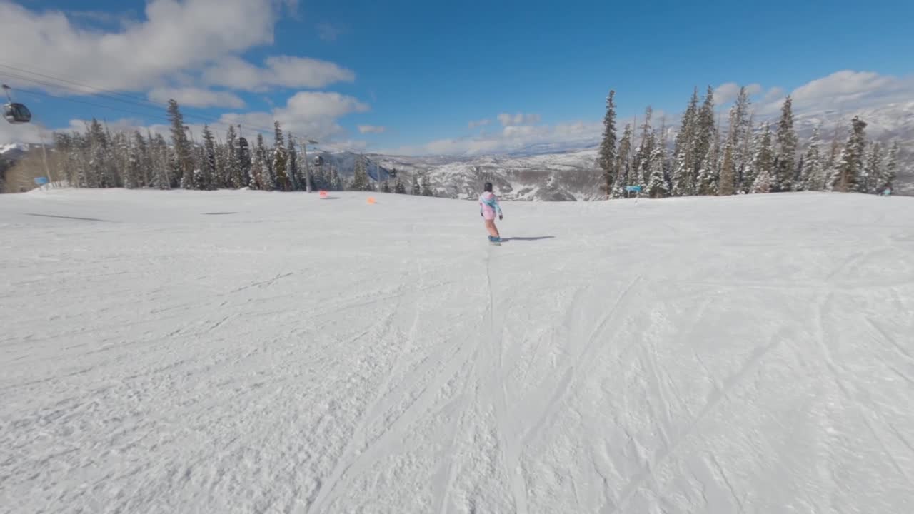 Female snowboarder performing an ollie. White winter slopes, Aspen, Colorado