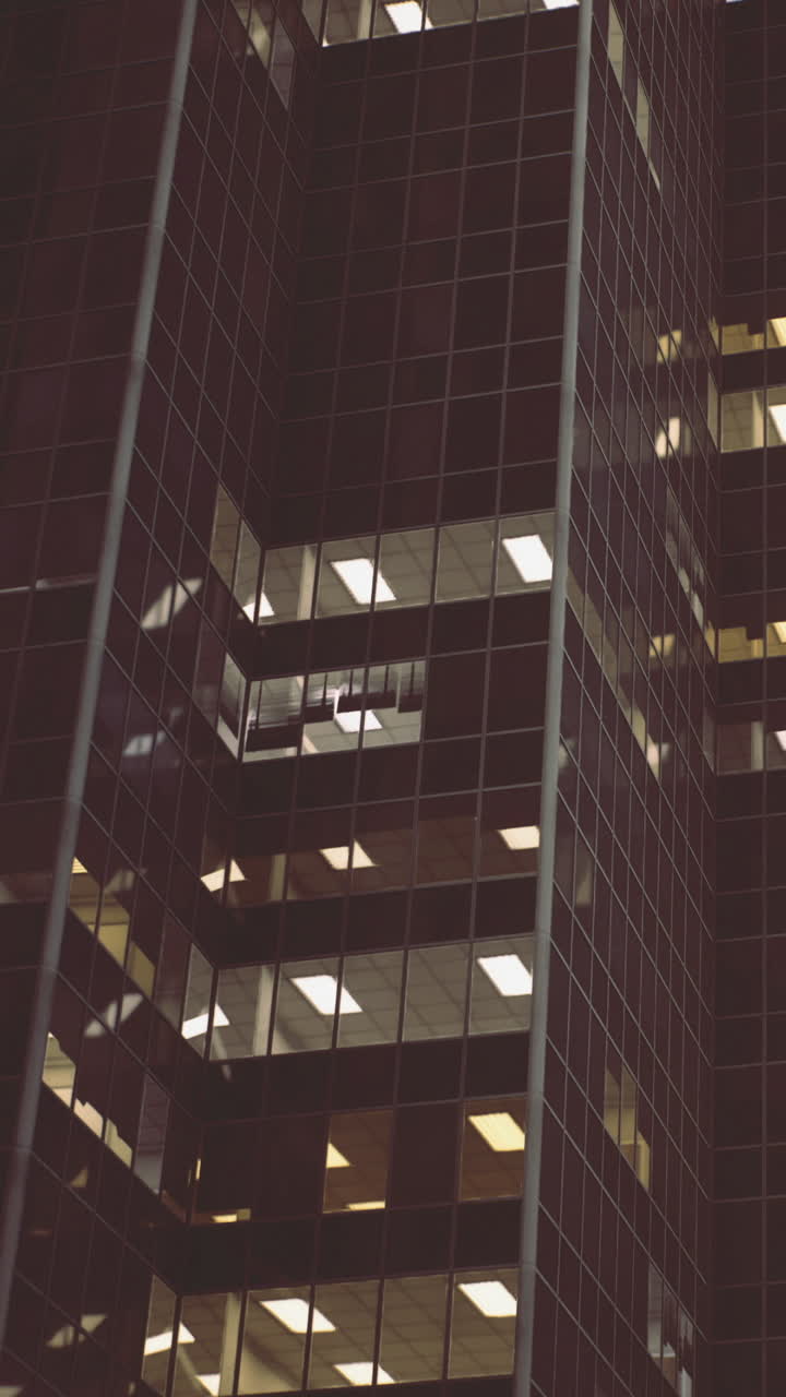 Luces en un edificio de la ciudad por la noche con reflejos en ventanas de cristal.