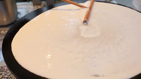 the chef spreads the pancake batter with a spatula