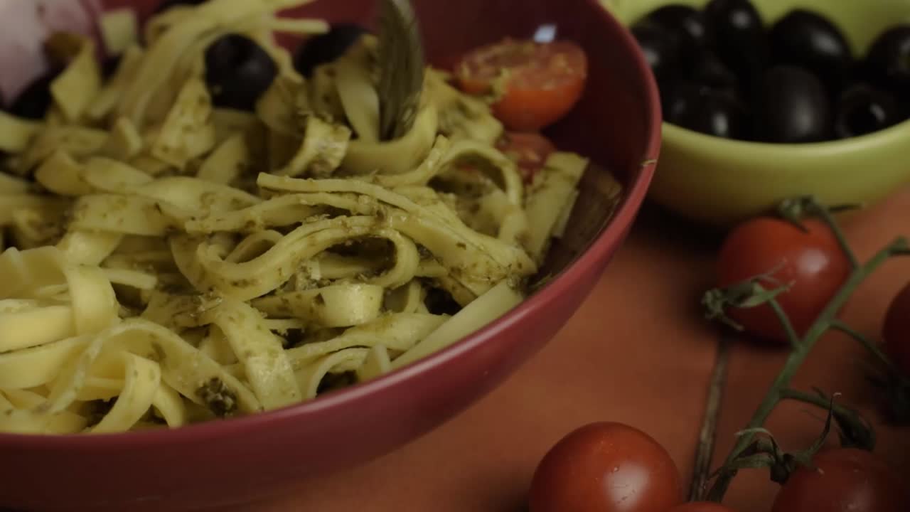 Serving of tagliatelle pasta with olives and tomatoes close up shot