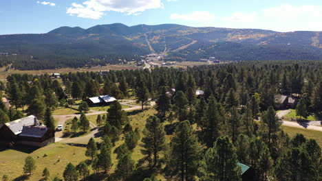 Aerial-descending-over-Angel-Fire,-New-Mexico-into-pine-trees