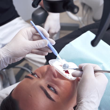 young woman laying in the dental chair. dentist treating patient's teeth in the dental office. stomatologist examines teeth through the microscope.