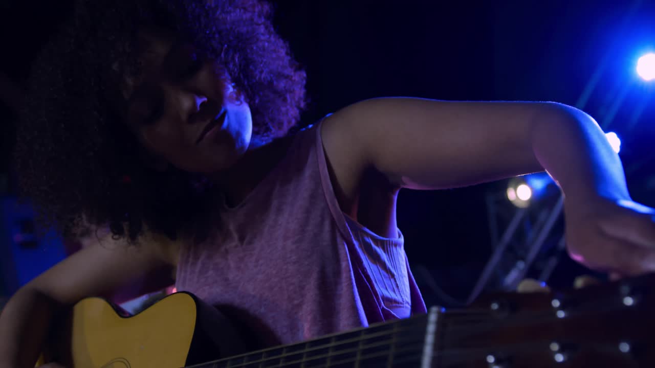 Female musician tuning her guitar before concert