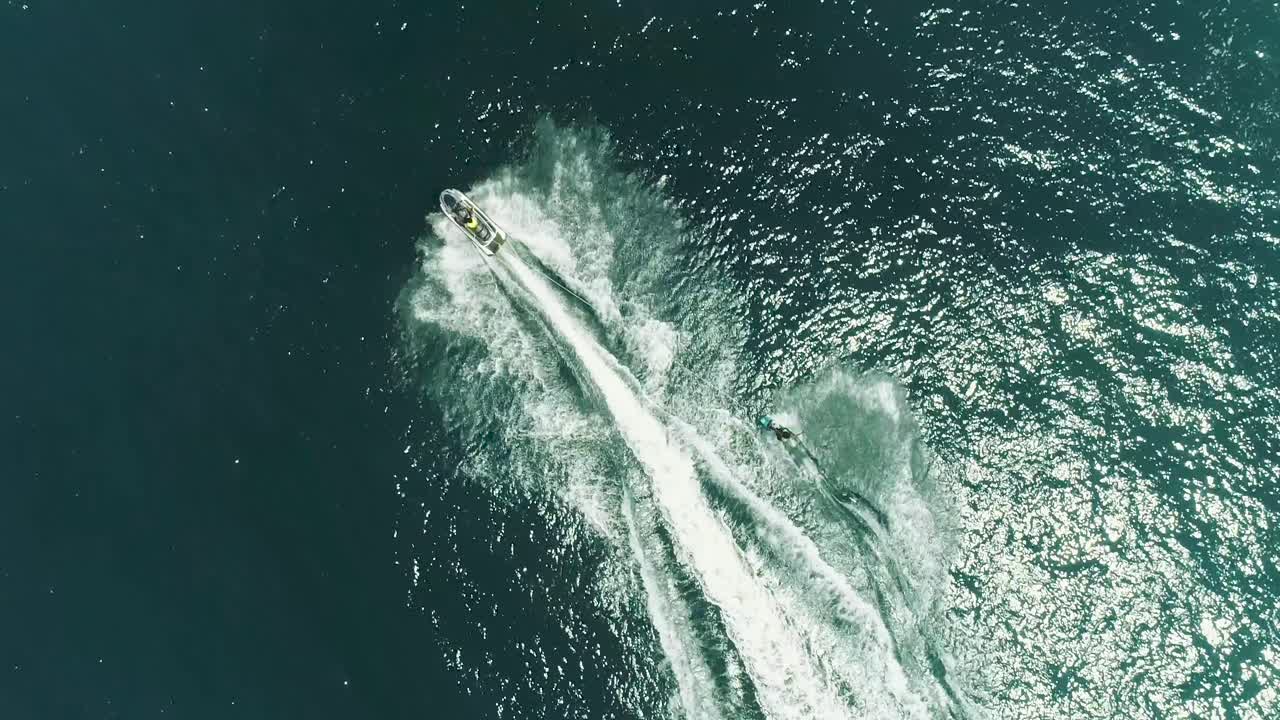熱帯の青と緑の海の水景でジェットスキーに乗るジェットスキーとサーフライダー。波が立つ海でのスポーツ活動を上空から撮影した映像。美しくアドレナリンが湧き出るエクストリームスポーツの光景