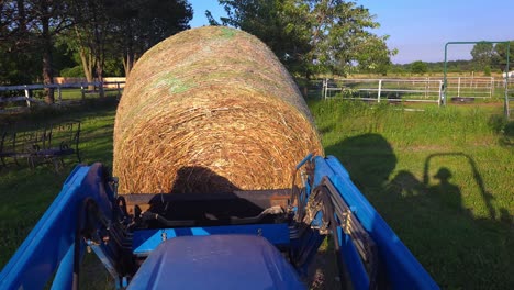 moving round bale of hay with a compact tractor on an american ranch