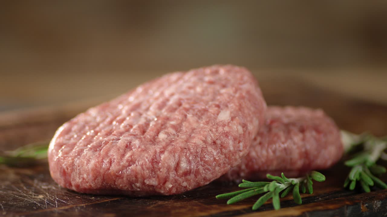 la carne cruda de la hamburguesa con una ramita de romero gira.