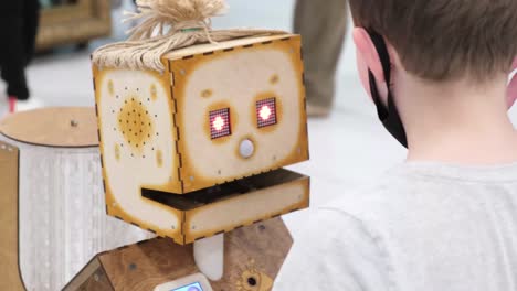 the child talks to a wooden robot the latest modern robotic technology the child talks to a wooden robot the latest modern robotic technology artificial intelligence