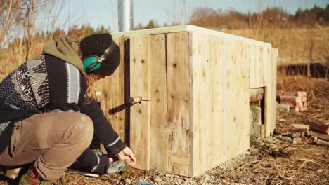 hombre construyendo hazlo tú mismo bañera de agua caliente de leña en un día soleado