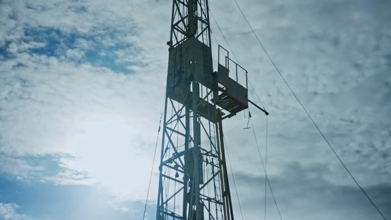 High metal tower with some wires attached. Low angle view on the support for drilling equipment in gas or oil production.
