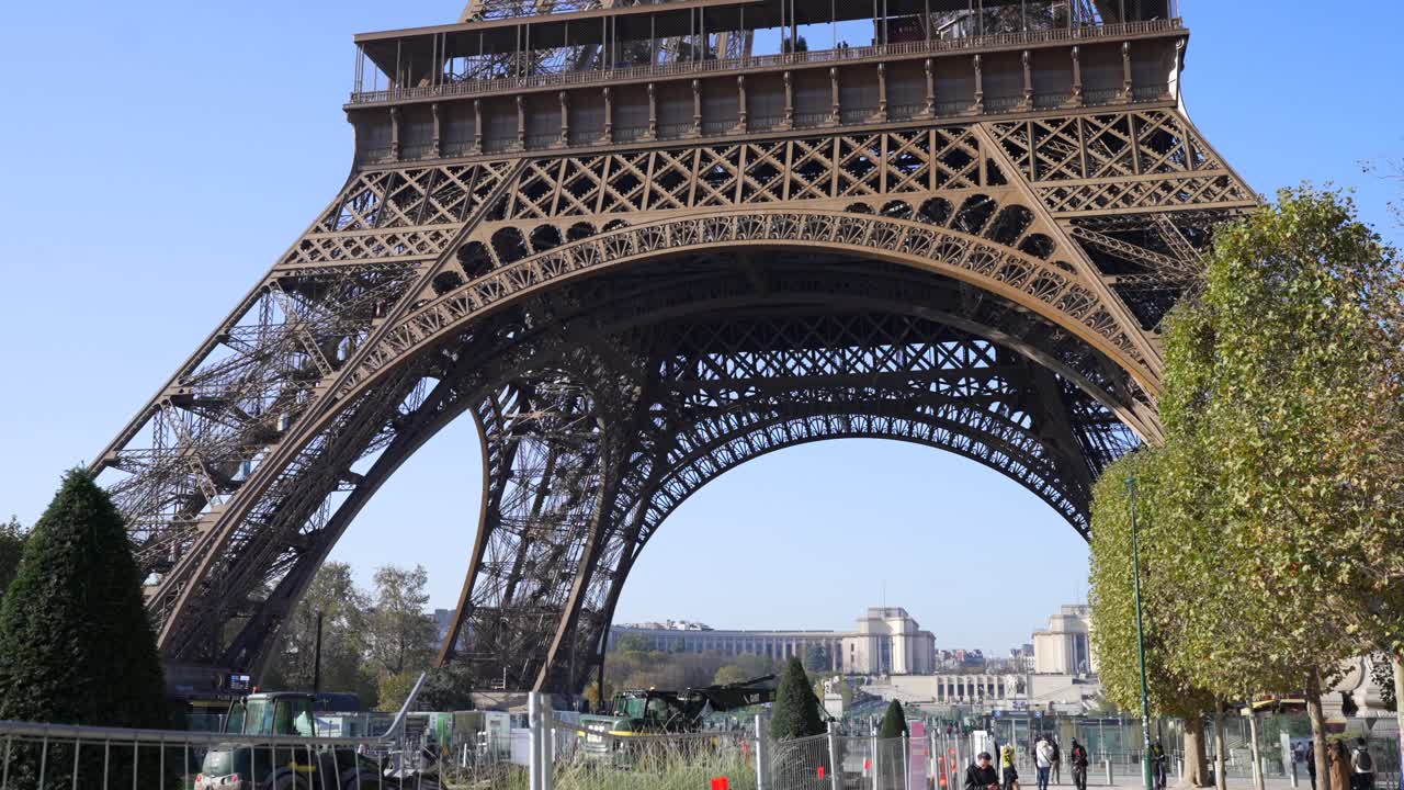 Construction crews work beneath the Eiffel Tower post-Olympics games on a sunny day, urban renovation in Paris,, in slow motion