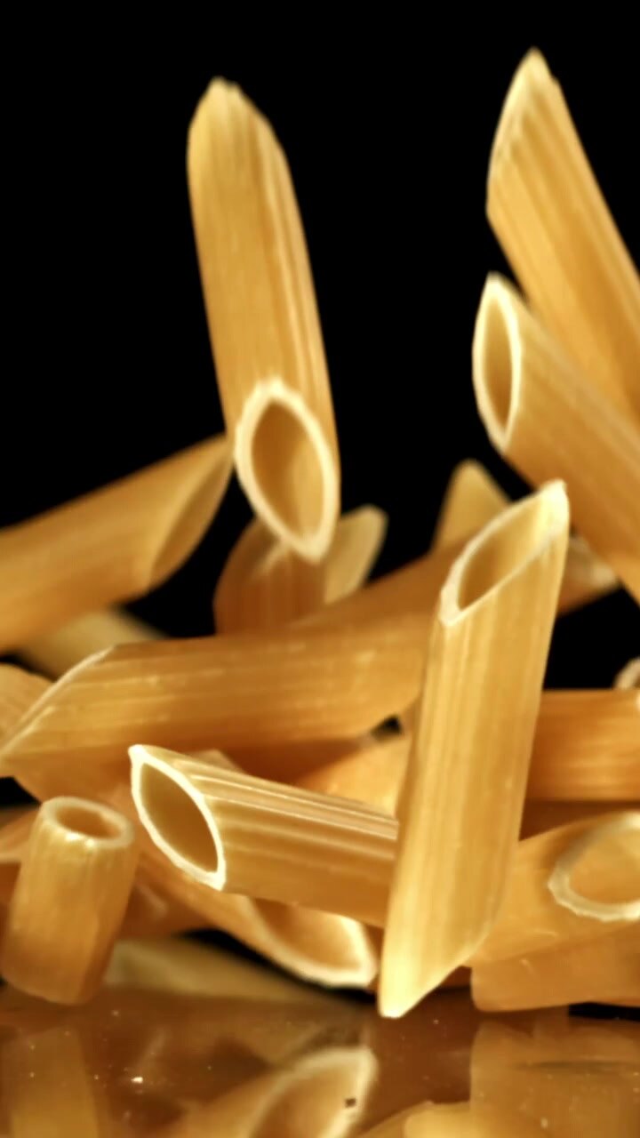 Pasta penne che cade al rallentatore su sfondo nero